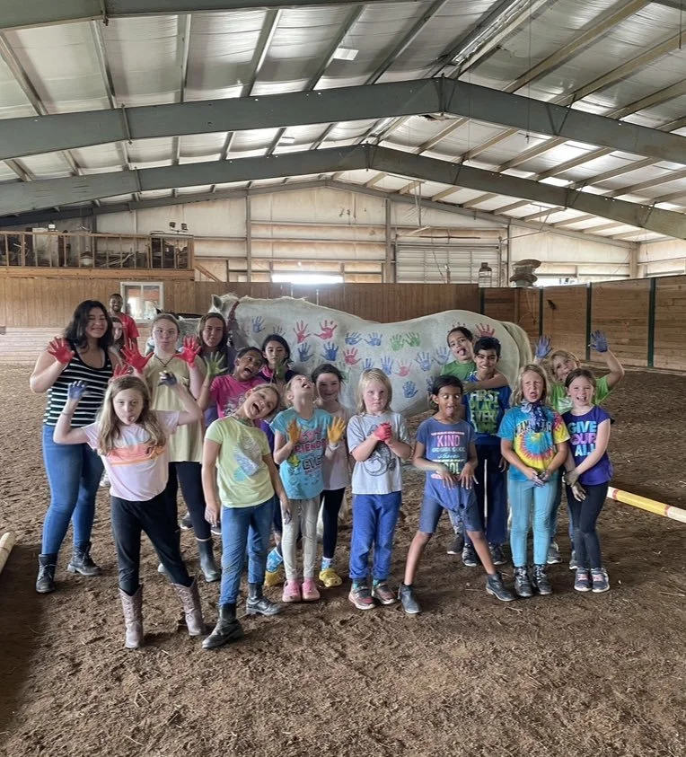 Group of camp kids with horses in the indoor arena