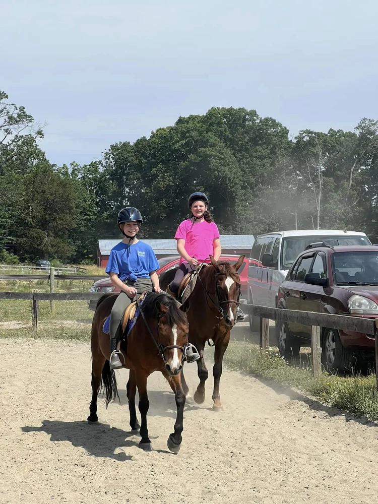 Two riders on horses in the outdoor arena