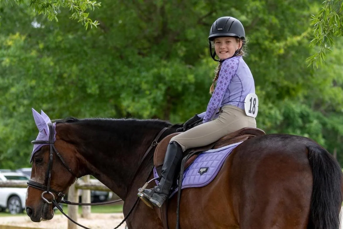 Young rider smiling on a bay horse at a show